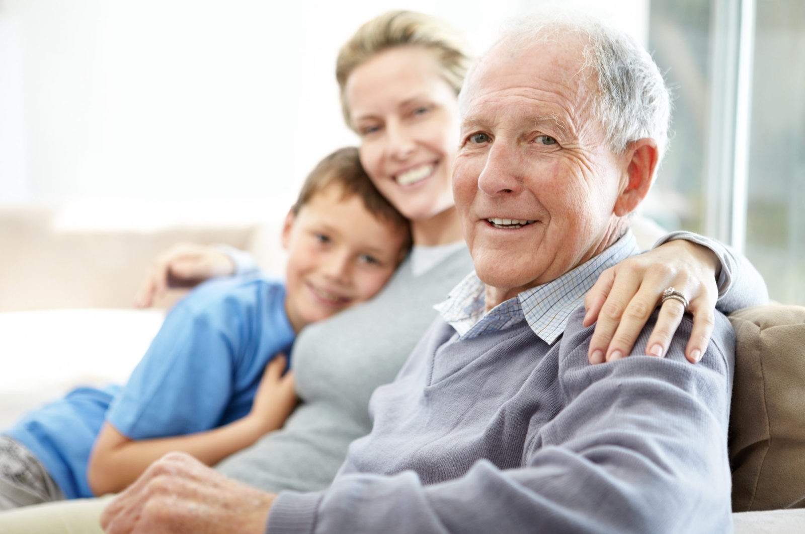 A old man and smiling and sitting with a women and a boy